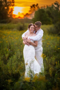Bride & groom in a field at sunset at Mt. Pleasant PohlCat golf course