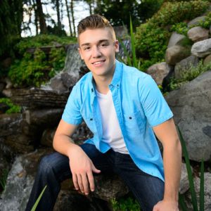 A close portrait of Nick leaning on a rock in front of a waterfall during his senior photo session.